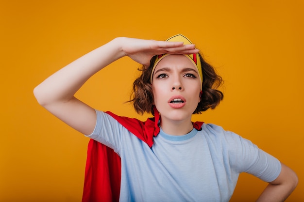 Free photo close-up portrait of funny superwoman posing emotionally on yellow space