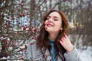 Free photo close up portrait of gentle girl in gray coat near the branches of a snowcovered tree