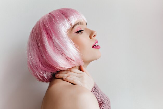 Close-up portrait of  girl in colorful peruke dreamy looking away. winsome pale lady isolated on light wall.