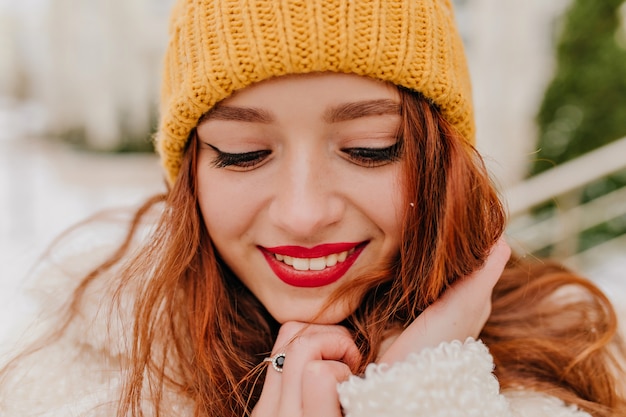 Free Photo close-up portrait of gorgeous girl with red lips. shy ginger woman in hat posing in winter.