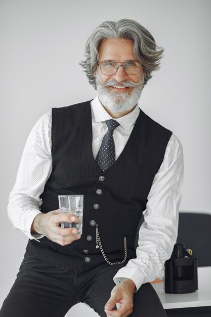 Close up portrait of grinning old-fashioned man.  Grandfather with glass of water.