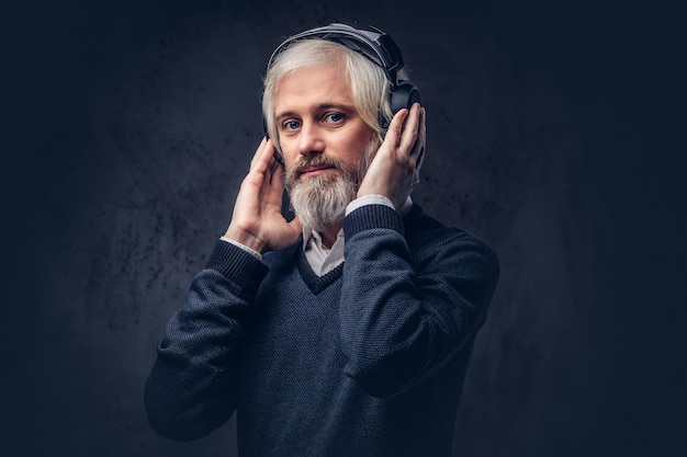 Free Photo close-up portrait of a handsome senior man listening to music in headphones. isolated a dark background.