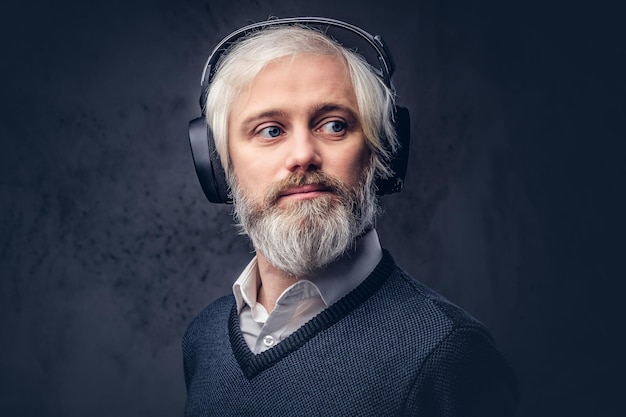 Free Photo close-up portrait of a handsome senior man listening to music in headphones. isolated a dark background.