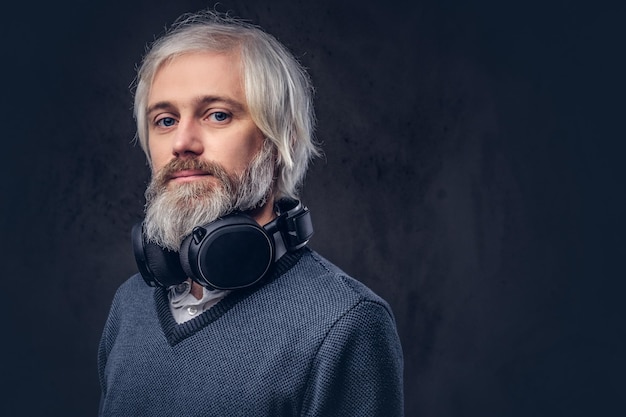 Free photo close-up portrait of a handsome senior man listening to music in headphones. isolated a dark background.