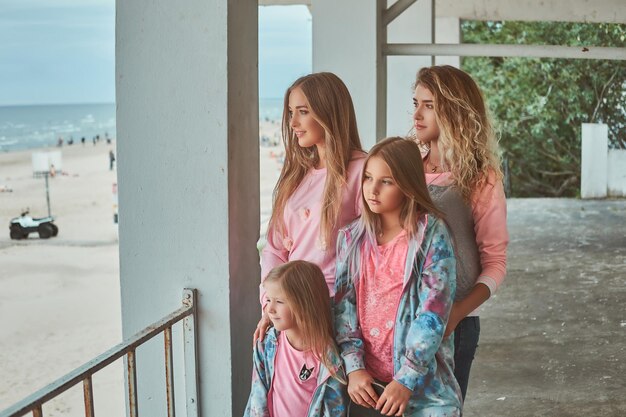 Close-up portrait of a happy family dressed in stylish clothes holds skateboard posing near a guardrail against a sea coast.