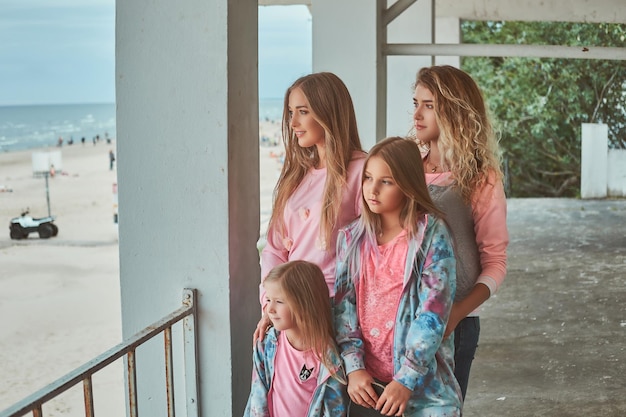 Close-up portrait of a happy family dressed in stylish clothes holds skateboard posing near a guardrail against a sea coast.