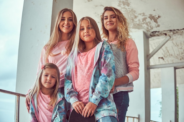 Free photo close-up portrait of a happy family dressed in stylish clothes holds skateboards posing near a guardrail against sea coast.