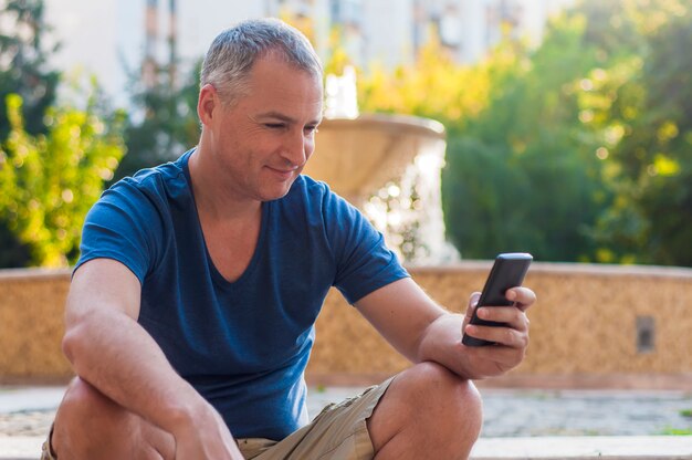 Close up portrait of happy smiling forty years old caucasian man talking on a mobile phone outdoor