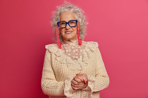 Close up portrait of happy wrinkled fashionable granny wearing glasses and sweater