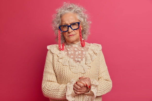 Close up portrait of happy wrinkled fashionable granny wearing glasses and sweater