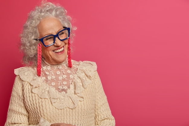 Close up portrait of happy wrinkled fashionable granny wearing glasses and sweater