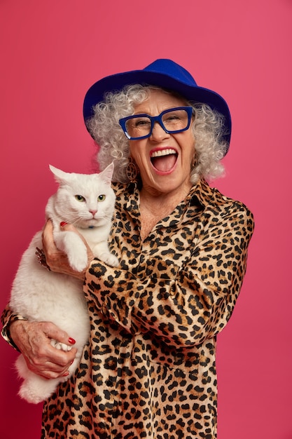 Free photo close up portrait of happy wrinkled fashionable granny with beautiful cat