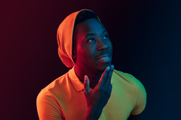 Free photo close up portrait of a happy young african american man smiling against black neon studio background