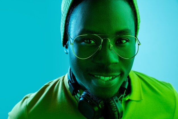 Close up portrait of a happy young african american man smiling against black neon studio