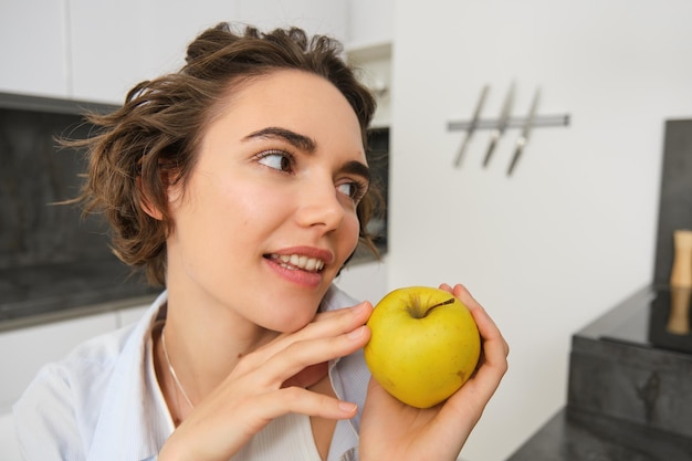 Close up portrait of healthy beautiful young woman holding an apple smiling