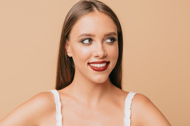 Close up portrait of lovely cute woman with bright make up and light-brown hair  on isolated wall with perfect smile