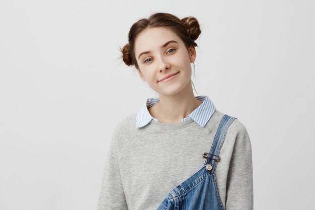 Close up portrait of lovely teen girl kind smile. Shining brunette woman with hair in double buns feeling good enjoying her youth. Beauty concept