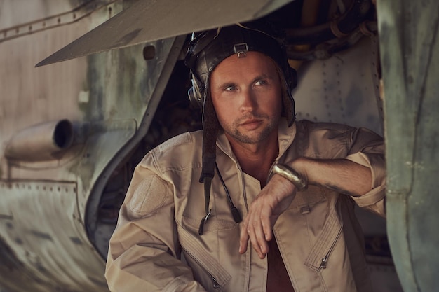 Free photo close-up portrait of a mechanic in uniform and flying near, standing under an old bomber airplane in the open air museum.