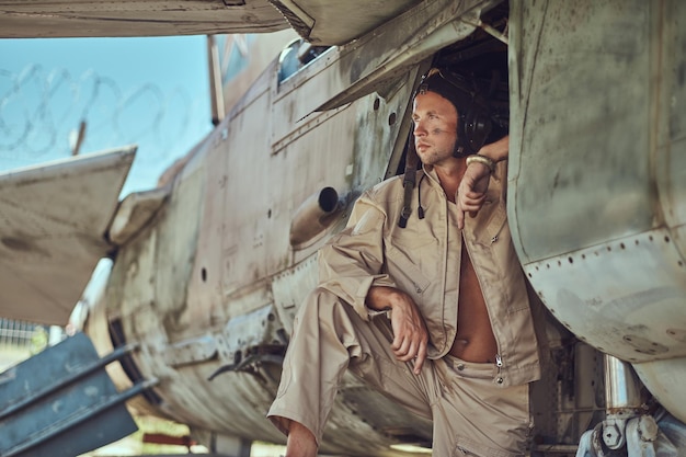 Free photo close-up portrait of a mechanic in uniform and flying near, standing under an old bomber airplane in the open air museum.