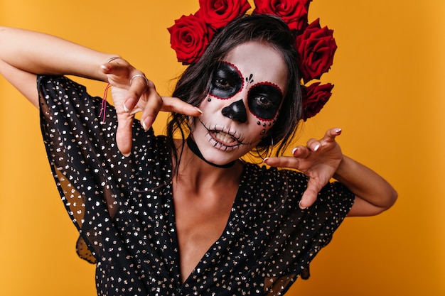 Free photo close-up portrait of mexican witch with painted face. woman posing in orange studio.