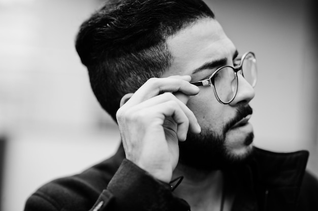 Close up portrait of middle eastern beard entrepreneur wear black coat and blue shirt eyeglasses against office building