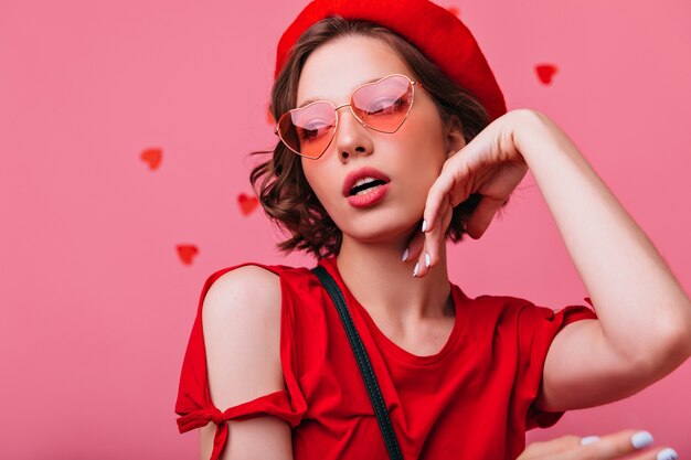 Close-up portrait of sensual pensive woman in red beret. Fashionable serious girl with short haircut posing.