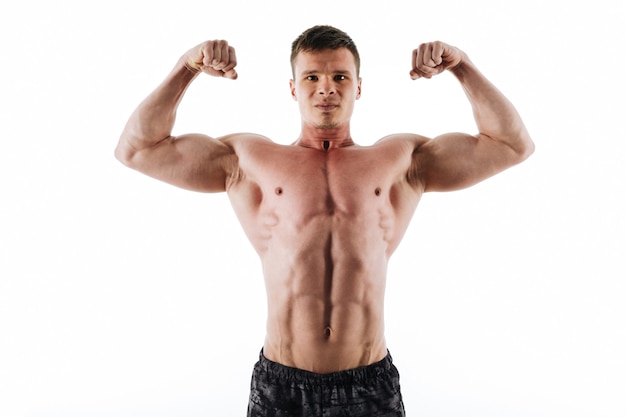 Free photo close-up portrait of serious strong sports man showing his biceps