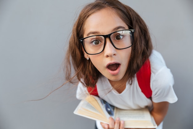 Close up portrait of shocked brunette schoolgirl in eyeglasses