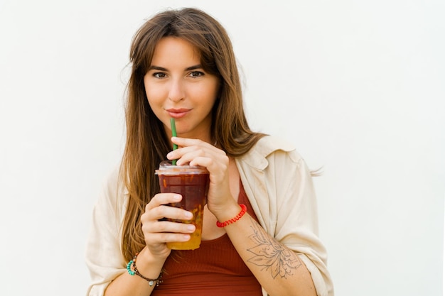 Close up portrait of Smiling european woman in stylish summer outfit drinking sweet lemonade on white background