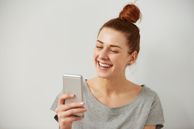 Close up portrait smiling or laughing young freelancer woman looking at phone