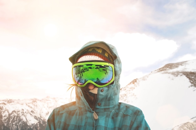 Free photo close up portrait of snowboarder posing in front of sunset and snowy mountains