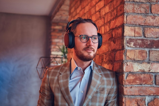 Free Photo close-up portrait of a stylish man in a flannel suit and glasses listening music.