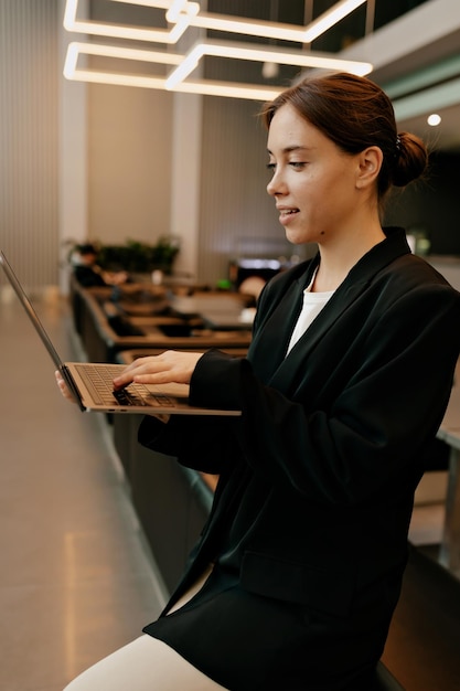 Free Photo close up portrait of stylish modern female model is typing on laptop in stylish office