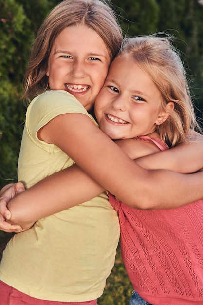 Free Photo close-up portrait of two happy girlfriends cuddling in the park.