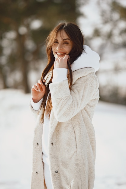 Close-up portrait of woman in black jacket. Woman standing in a forest in snowy day.