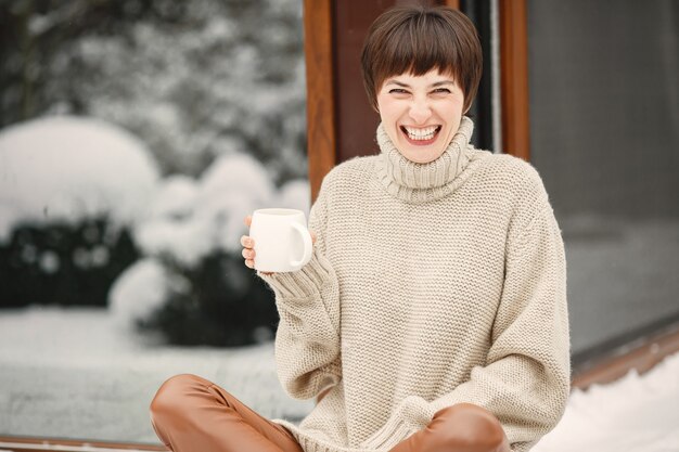 Close-up portrait of woman in white sweater, drinking tea