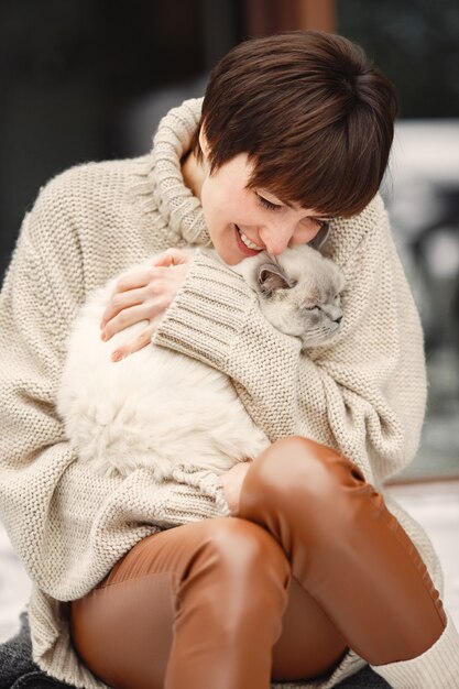 Close-up portrait of woman in white sweater with white cat