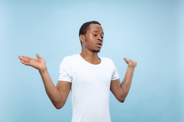 close up portrait of young african-american man in white shirt.. Showing empty bar, pointing, choosing, inviting.