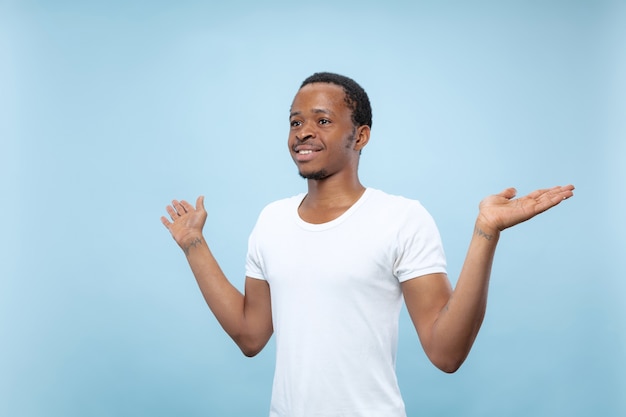 close up portrait of young african-american man in white shirt.. Showing empty bar, pointing, choosing, inviting.