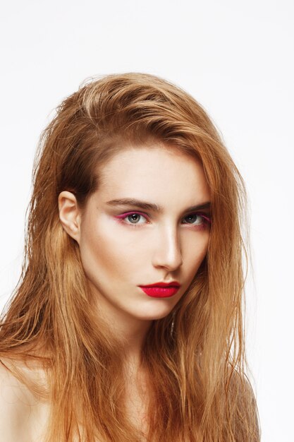 Close-up portrait of young beautiful confident sad girl with bright make up. white wall. Isolated.