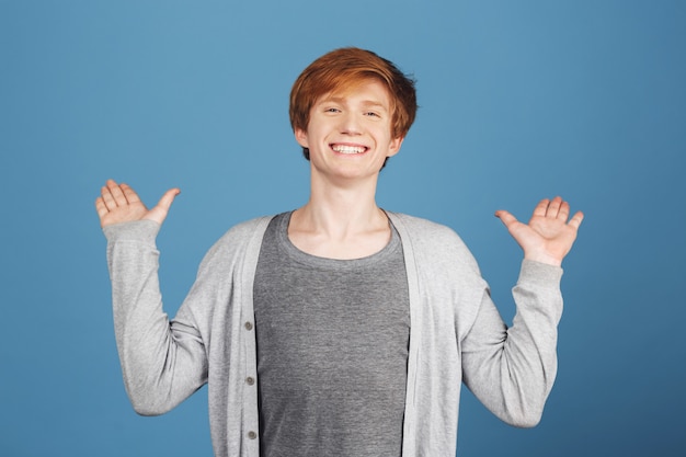 Close up portrait of young cheerful happy beautiful red-haired student in stylish casual outfit spreading hands with excited expression, seeing best friend after a long time.