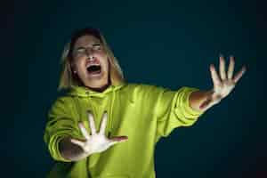 Free photo close up portrait of young crazy scared and shocked caucasian woman isolated on dark background.