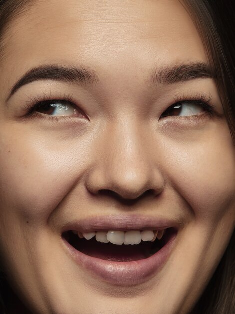 Close up portrait of young and emotional chinese woman. Highly detail photoshot of female model with well-kept skin and bright facial expression. Concept of human emotions. Looking up, smiling.