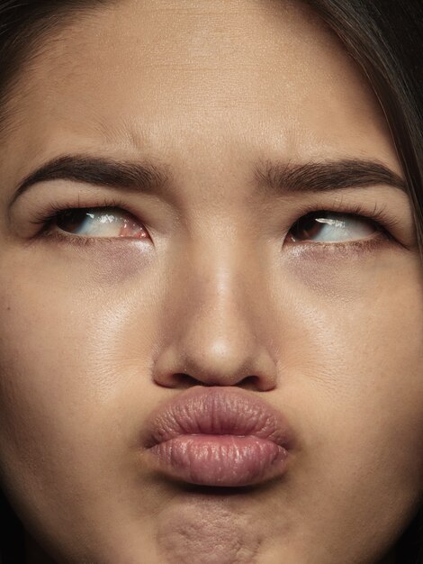 Close up portrait of young and emotional chinese woman. Highly detail photoshot of female model with well-kept skin and bright facial expression. Concept of human emotions. Thinking, looks sad.