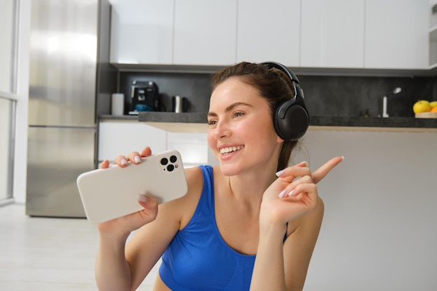 Free photo close up portrait of young happy woman workout at home listens music in wireless headphones singing