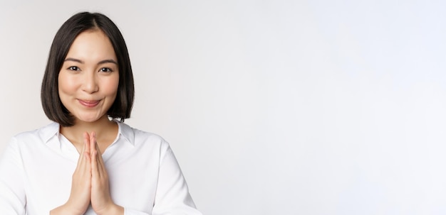 Free Photo close up portrait of young japanese woman showing namaste thank you arigatou gesture standing over white background