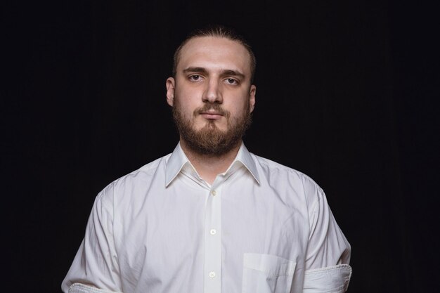 Close up portrait of young man isolated on black studio background