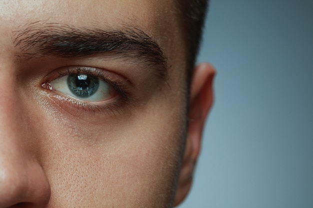 Free Photo close-up portrait of young man isolated on grey studio background. caucasian male model's face and blue eye. concept of men's health and beauty, self-care, body and skin care, medicine or phycology.