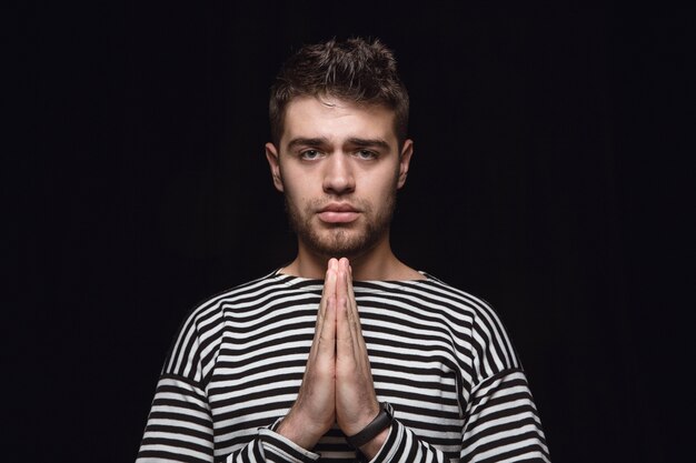 Free photo close up portrait of young man isolated. praying looking forward, sad and hopeful. facial expression, human emotions concept.