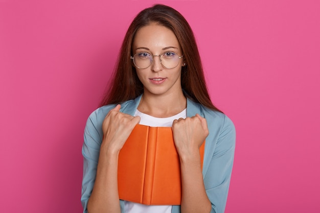 Free photo close up portrait of young woman with glasses holding text book organaiser